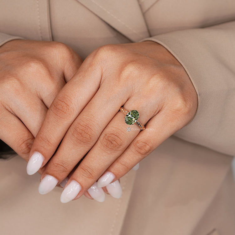Oval cut ring with green diamond and bridge accent.