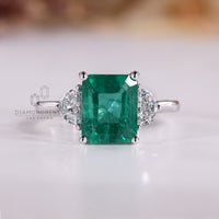Emerald cut emerald ring half moon three stone style.
