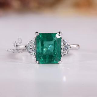 Emerald cut emerald ring half moon three stone style.
