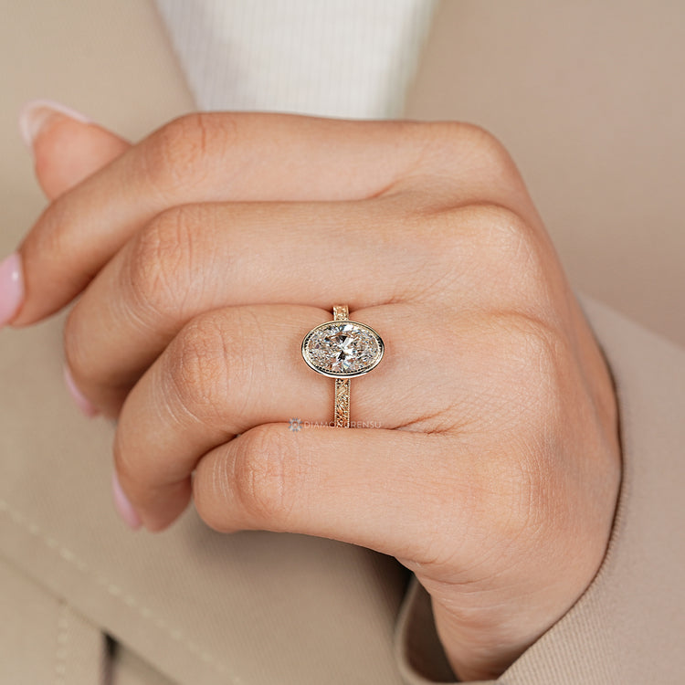 Oval diamond solitaire ring with bezel setting.