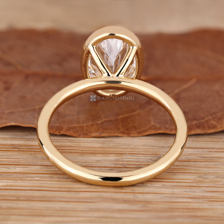 Oval diamond ring featuring a bezel set centre stone.