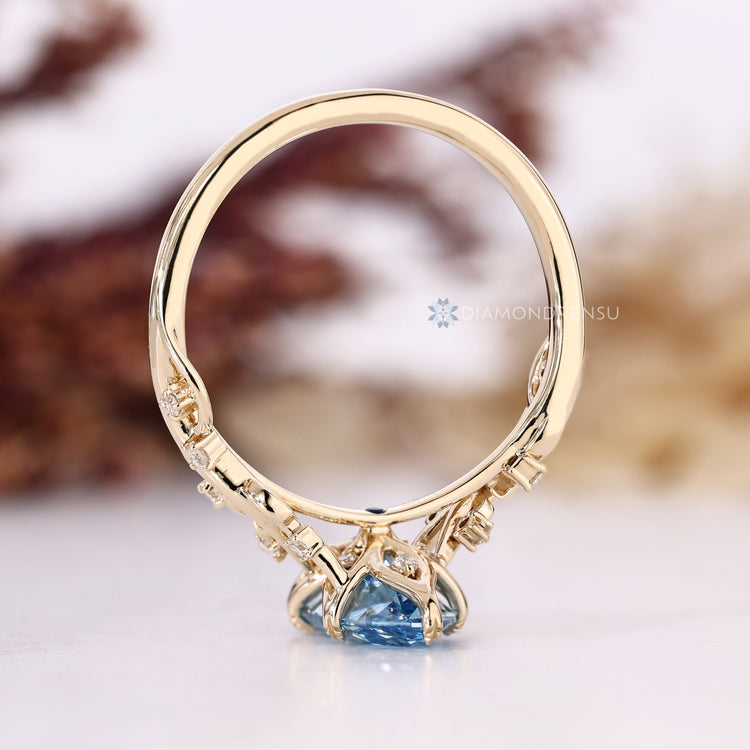 Blue diamond ring with nature inspired leaf prongs.