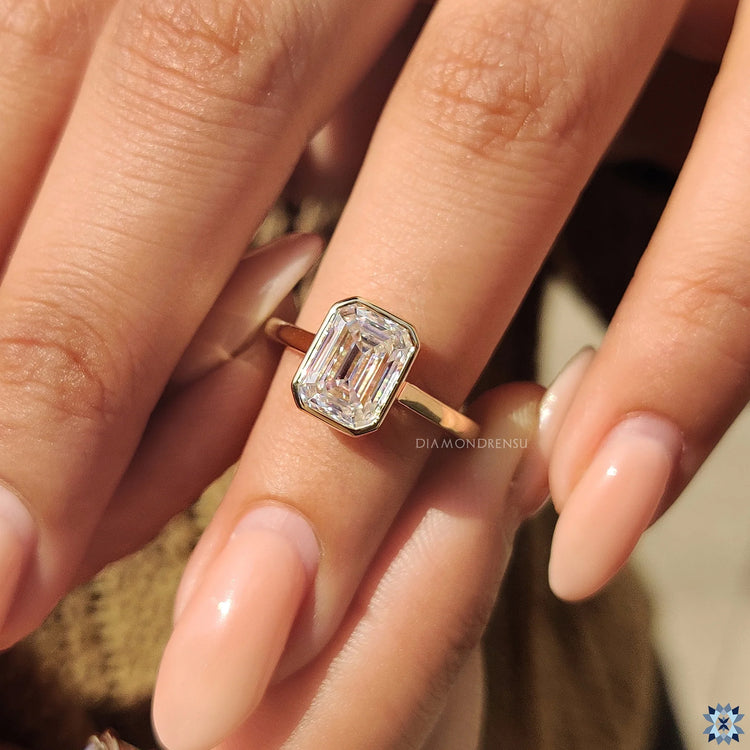 Yellow gold ring featuring a stunning bezel set Emerald cut diamond.