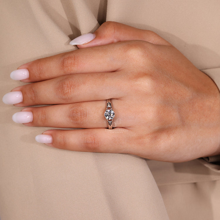 4 prong white gold ring with round diamond and side stones.
