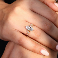 Round cut side stones on a yellow gold cluster diamond engagement ring.
