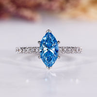 Marquise diamond engagement ring with blue sapphire accent.
