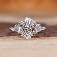 Oval diamond ring with marquise and round side stones.
