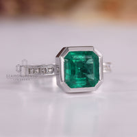 Emerald gemstone ring Asscher cut bezel channel style.
