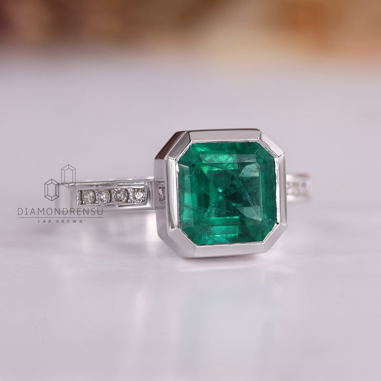 Emerald gemstone ring Asscher cut bezel channel style.
