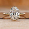 Oval cut diamond ring with solitaire bezel setting.