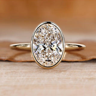 Oval cut diamond ring with solitaire bezel setting.