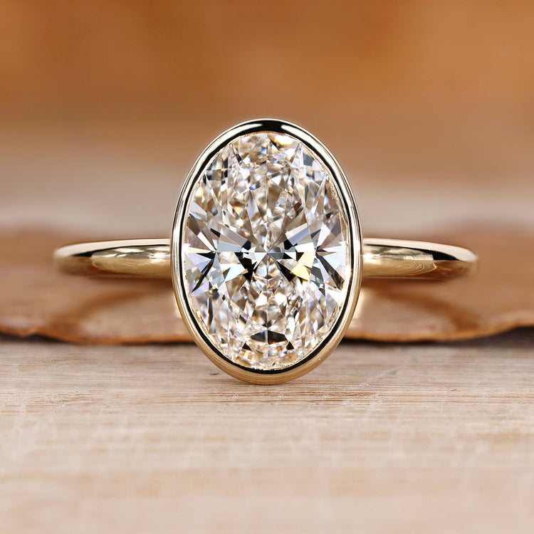 Oval cut diamond ring with solitaire bezel setting.