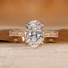 Oval cut diamond ring with round bridge accents.