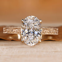 Oval cut diamond ring with round bridge accents.
