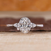 Oval cut diamond ring with pear cut side stones and round halo setting.
