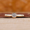 Round cut diamond ring in yellow gold with bezel setting.
