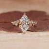 Cluster diamond ring with marquise cut center stone in yellow gold.

