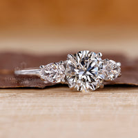 Three stone round diamond ring pear side stones style.
