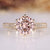 Round diamond ring with pink diamond accent.