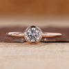 Solitaire diamond ring with round diamond in a smooth bezel setting.
