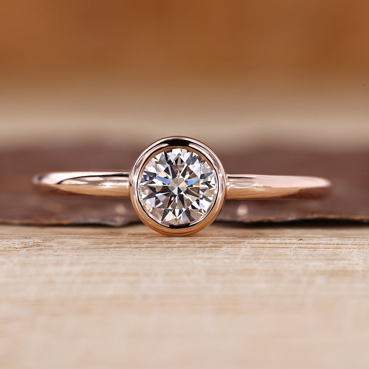 Solitaire diamond ring with round diamond in a smooth bezel setting.
