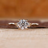 Round diamond ring in three stone style with pear shape outline.