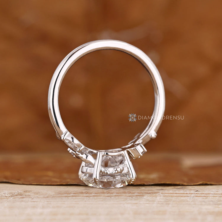 Round diamond ring with marquise side stones and leaf prongs.