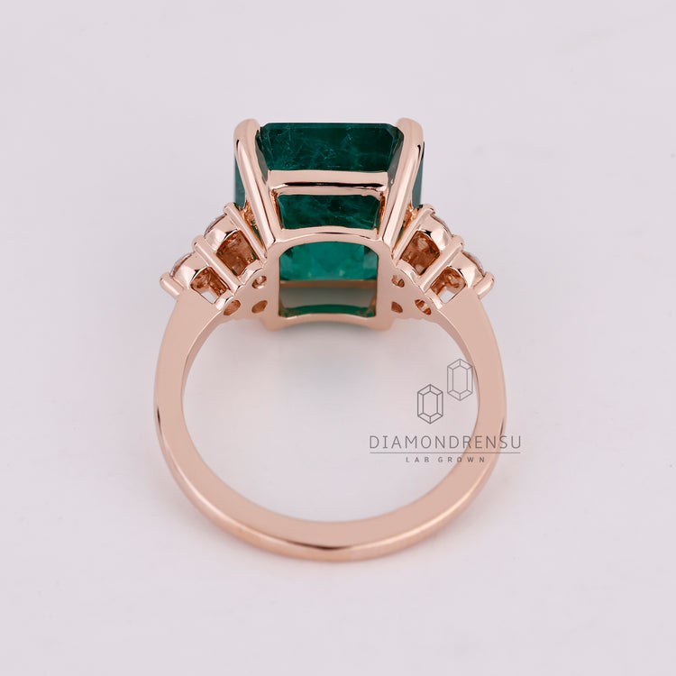 Emerald ring round side stones muse setting style.
