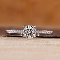 Round cut diamond ring pave tapered shank four prong.
