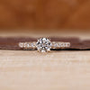 Round diamond ring with pave setting and four claw prong design.
