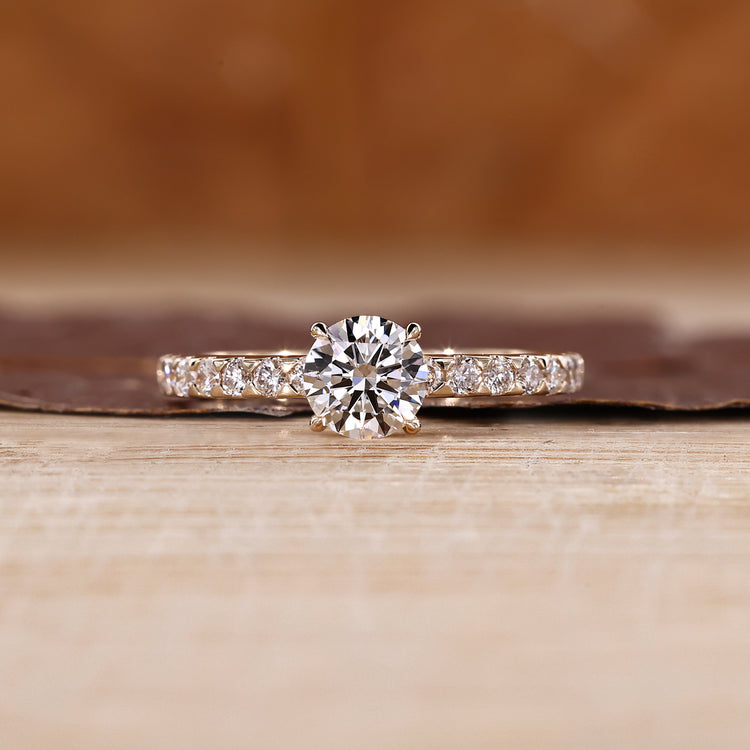 Round diamond ring with pave setting and four claw prong design.
