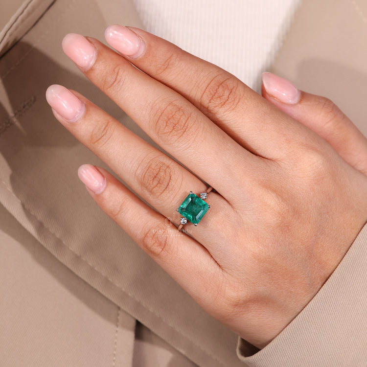 Emerald gemstone ring hidden halo prong setting style.
