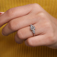 Round cut ring pear side stones four claw prong set.

