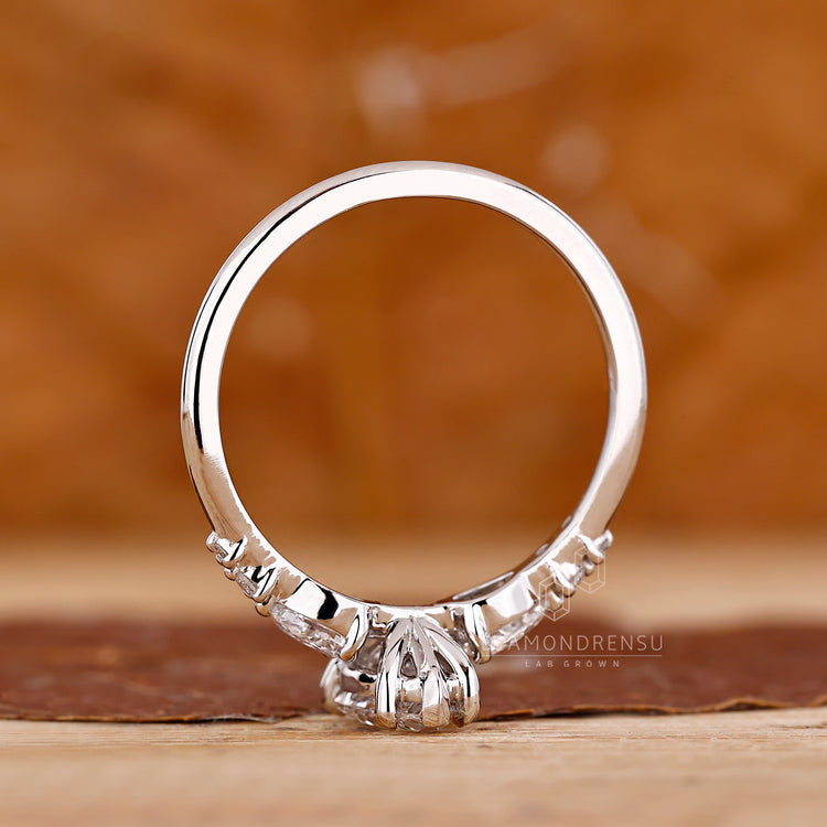 Pear diamond ring round side stones five claw prong.
