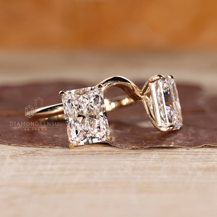 Curved style radiant cut diamond ring with claw prongs.

