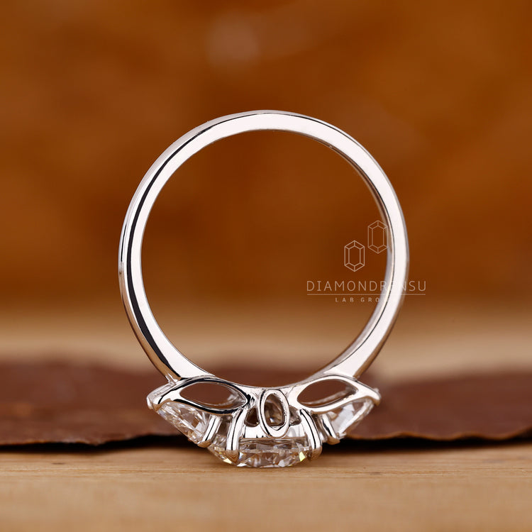 Round diamond ring pear side stones prong set.

