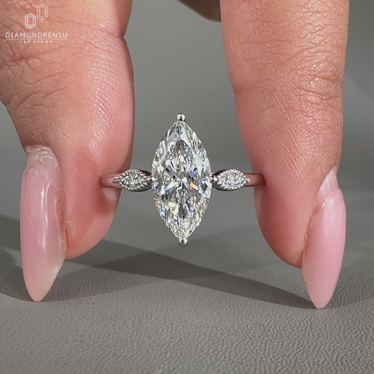 3 stone ring featuring a marquise centre and round side stones.
