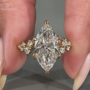 Marquise cut diamond ring with round side stones on a gold band.
