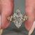 Marquise cut diamond ring with round side stones on a gold band.
