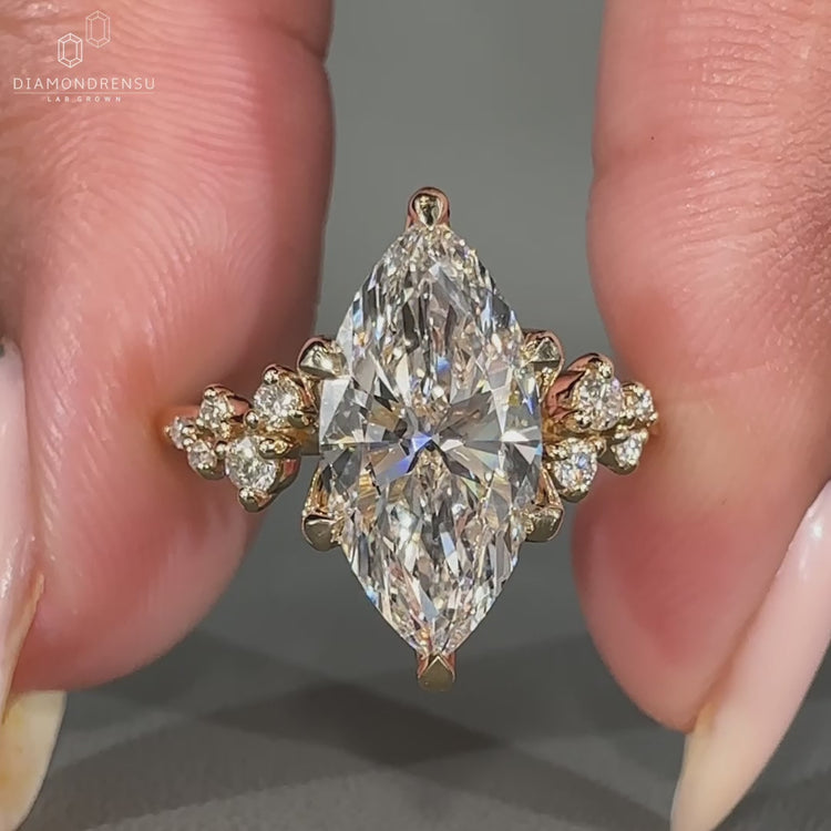 Marquise cut diamond ring with round side stones on a gold band.
