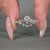 Round cut diamond ring with pavé and milgrain setting in white gold.
