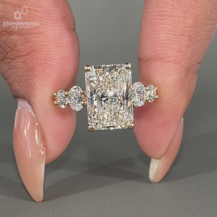 Yellow gold engagement ring with oval and round side stone.
