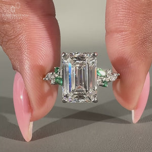 Emerald diamond ring in muse setting with side stones in white gold.

