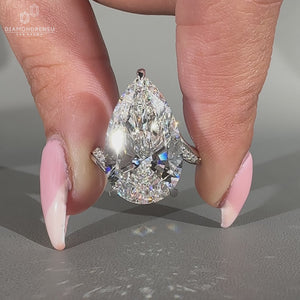 Pave round diamond ring featuring pear cut centre stone.