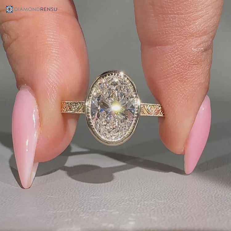 Oval diamond ring with milgrain detailing.