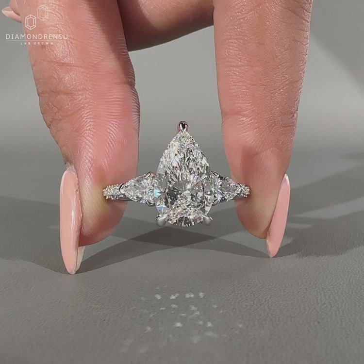 Handmade cathedral diamond ring with pear and round side stones.
