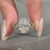 Twisted pave ring with round diamond halo setting in yellow gold.

