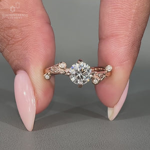 Round cut diamond ring with round side stones in a rose gold band.

