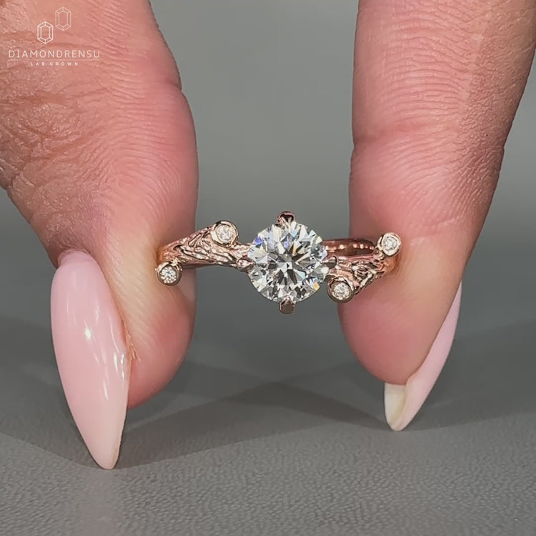 Round cut diamond ring with round side stones in a rose gold band.
