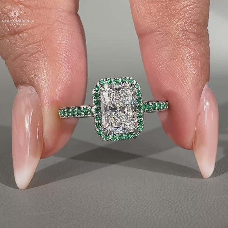 Round cut emerald ring featuring an emerald halo set in a handcrafted white gold band.
